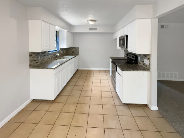 kitchen with light tile flooring, backsplash, sink, white cabinetry, and appliances with stainless steel finishes