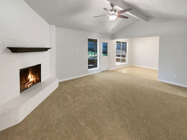 unfurnished living room featuring a textured ceiling, vaulted ceiling with beams, light carpet, a brick fireplace, and ceiling fan