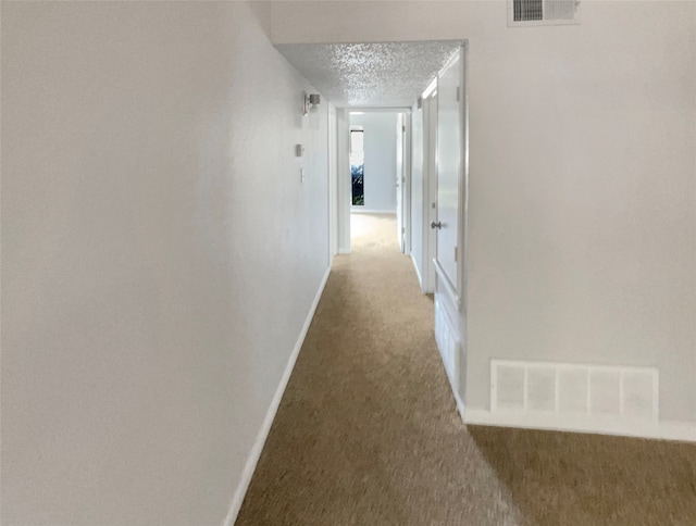 corridor with carpet and a textured ceiling