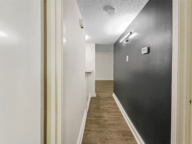 corridor featuring a textured ceiling and hardwood / wood-style floors