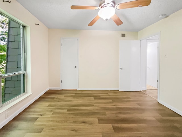 empty room with a textured ceiling, wood-type flooring, and ceiling fan