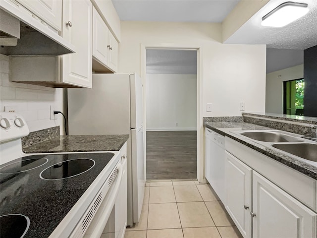 kitchen with white dishwasher, stove, white cabinets, sink, and light tile flooring