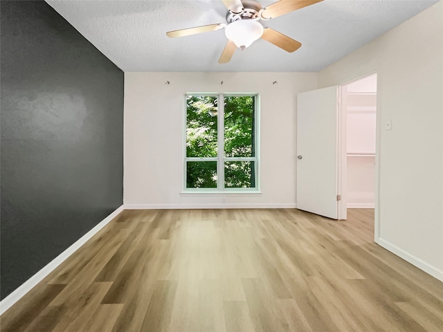 unfurnished room featuring a textured ceiling, ceiling fan, and light wood-type flooring