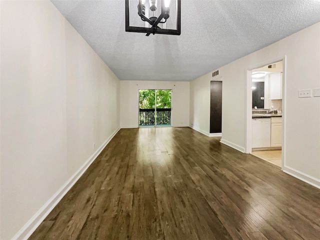 interior space featuring an inviting chandelier, a textured ceiling, and dark wood-type flooring