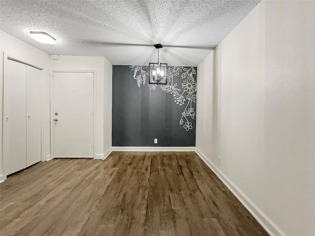 unfurnished dining area with a textured ceiling, a chandelier, and wood-type flooring