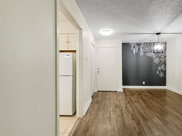 corridor with hardwood / wood-style floors, a chandelier, and a textured ceiling