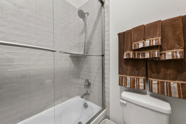 bathroom featuring combined bath / shower with glass door and toilet