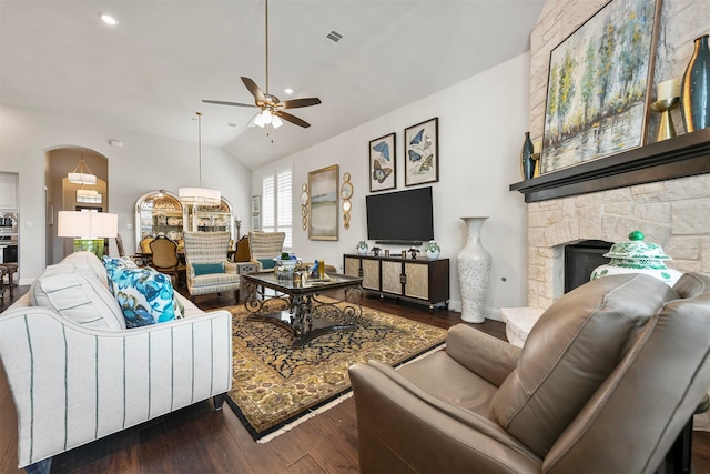 living room featuring ceiling fan, a stone fireplace, dark hardwood / wood-style flooring, and vaulted ceiling