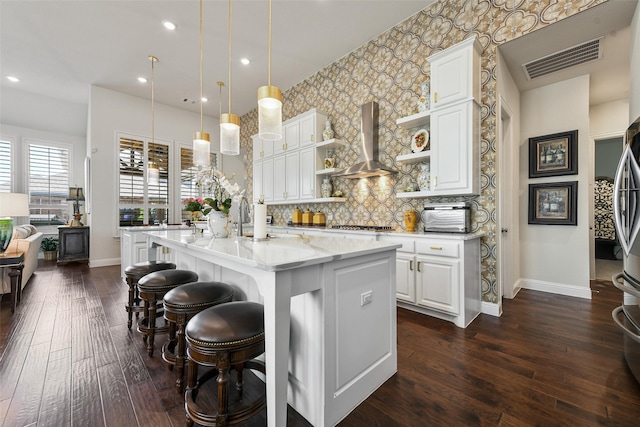 kitchen featuring white cabinetry, light stone countertops, wall chimney exhaust hood, and dark wood-type flooring