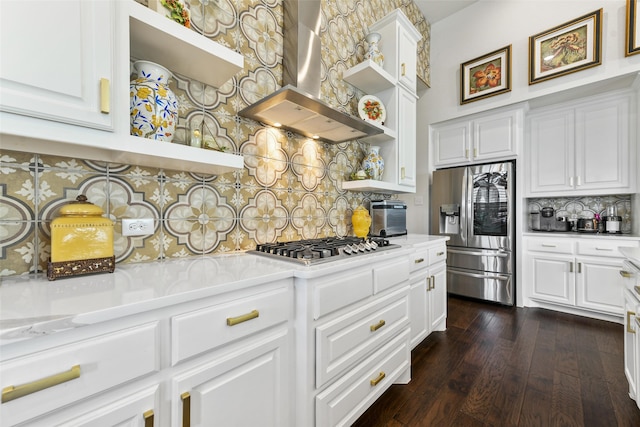 kitchen with wall chimney range hood, decorative backsplash, white cabinets, and appliances with stainless steel finishes