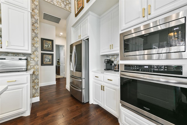 kitchen featuring dark wood-type flooring, white cabinets, backsplash, and stainless steel appliances