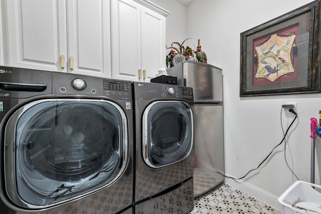 laundry room with light tile patterned flooring, cabinets, and washing machine and clothes dryer