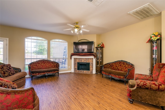 living room featuring hardwood / wood-style flooring, a tile fireplace, and ceiling fan