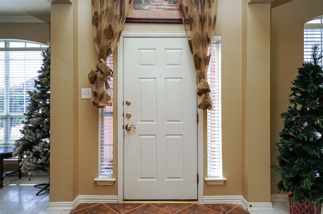 foyer entrance featuring tile flooring and crown molding