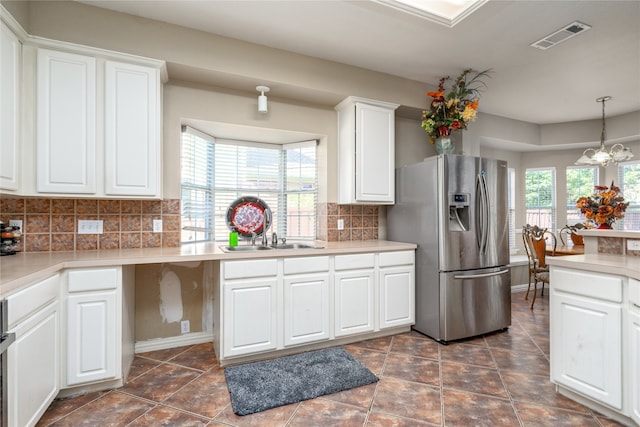 kitchen with a wealth of natural light, stainless steel fridge with ice dispenser, white cabinetry, and tasteful backsplash