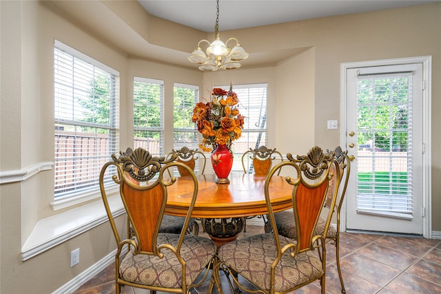 dining space with an inviting chandelier, dark tile flooring, and a raised ceiling