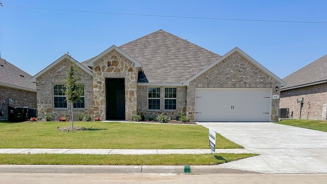 view of front of property with a garage, central AC unit, and a front yard