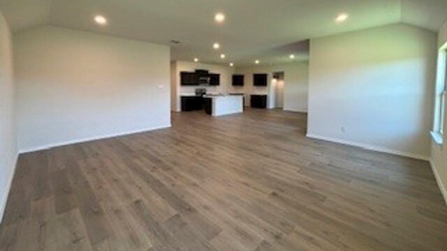 unfurnished living room featuring wood-type flooring and vaulted ceiling