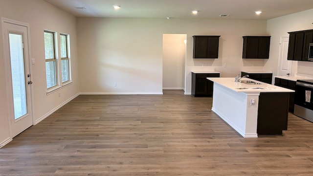 kitchen featuring range, hardwood / wood-style flooring, a center island with sink, and plenty of natural light