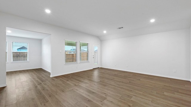 empty room with vaulted ceiling and wood-type flooring