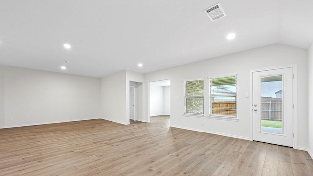 spare room with lofted ceiling, plenty of natural light, and light hardwood / wood-style flooring