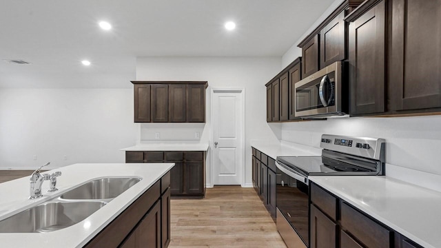 kitchen featuring sink, dark brown cabinets, stainless steel appliances, and light hardwood / wood-style flooring