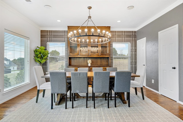 dining space featuring a notable chandelier, light hardwood / wood-style flooring, and crown molding