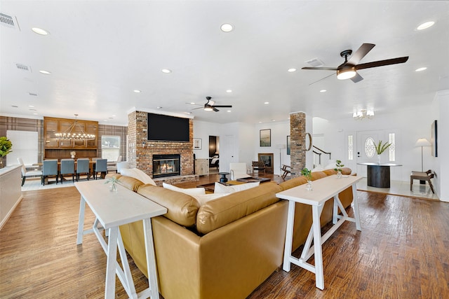 living room featuring brick wall, hardwood / wood-style flooring, ceiling fan, and a fireplace