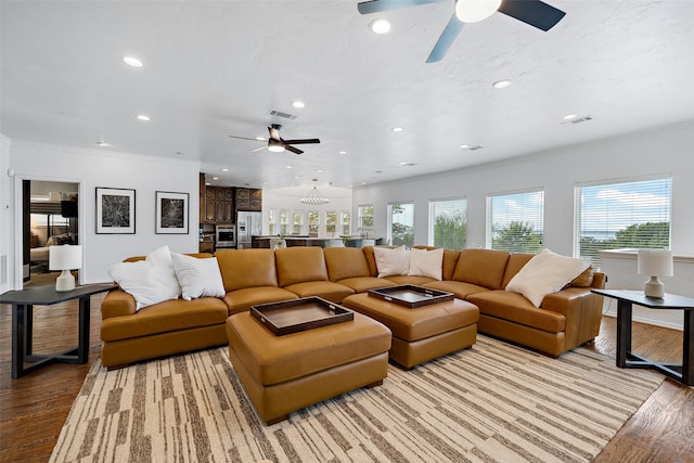 living room featuring hardwood / wood-style flooring, ornamental molding, and ceiling fan