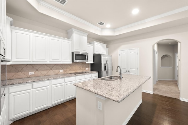 kitchen featuring sink, appliances with stainless steel finishes, a kitchen island with sink, white cabinets, and a raised ceiling