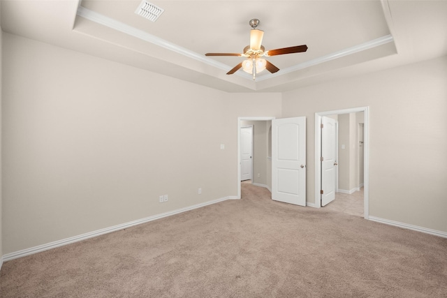 unfurnished room with a raised ceiling, ornamental molding, light colored carpet, and ceiling fan