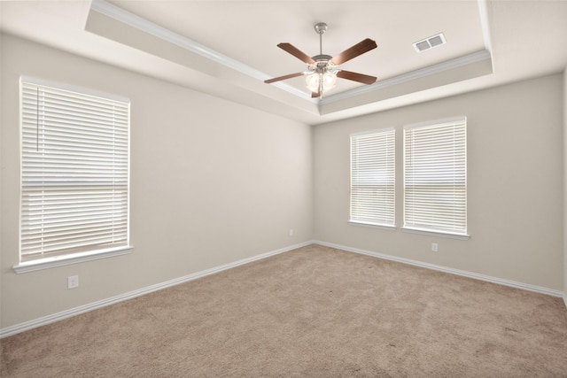 carpeted empty room featuring crown molding, a raised ceiling, and ceiling fan