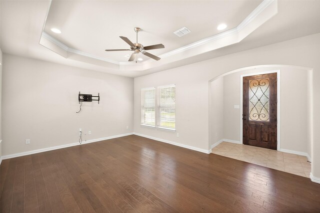 foyer entrance featuring ceiling fan, wood-type flooring, crown molding, and a tray ceiling