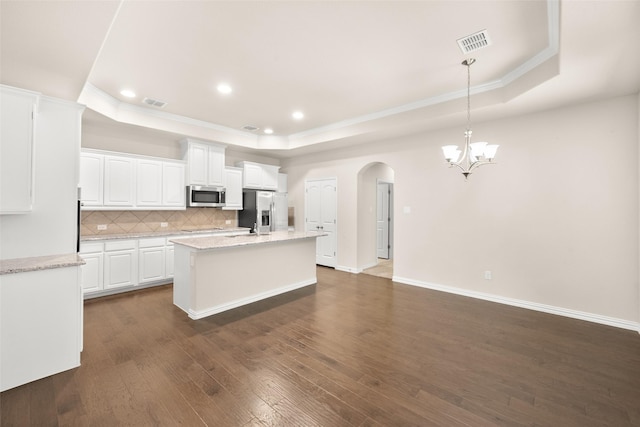 kitchen featuring white cabinetry, hanging light fixtures, a tray ceiling, and stainless steel appliances