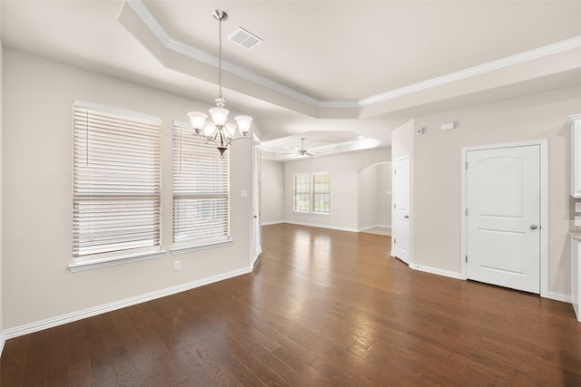 unfurnished living room with dark wood-type flooring, a tray ceiling, ceiling fan with notable chandelier, and crown molding