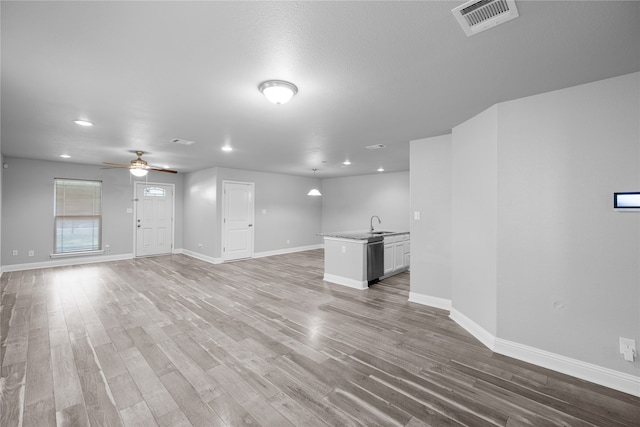 unfurnished living room with ceiling fan, sink, and light hardwood / wood-style floors