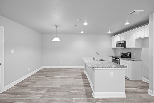 kitchen with light stone counters, stainless steel appliances, sink, pendant lighting, and white cabinetry