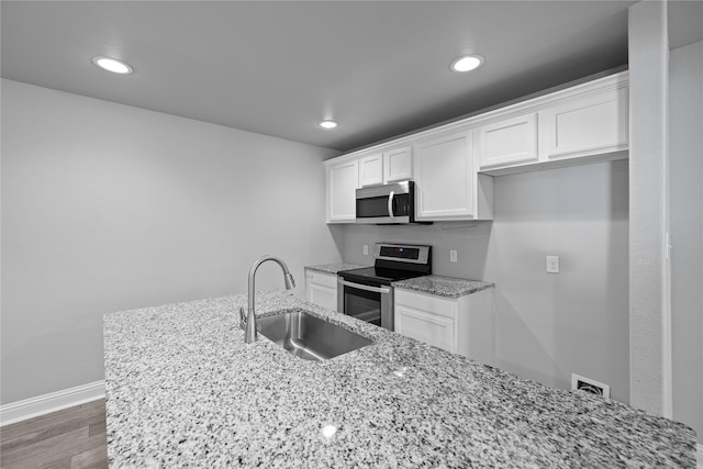 kitchen featuring sink, stainless steel appliances, light stone counters, dark hardwood / wood-style flooring, and white cabinets