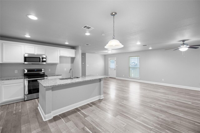 kitchen featuring white cabinets, appliances with stainless steel finishes, decorative light fixtures, and sink