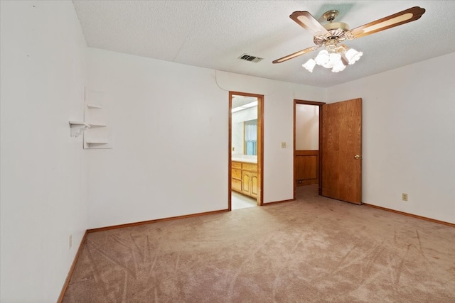 spare room featuring visible vents, baseboards, light carpet, a textured ceiling, and a ceiling fan