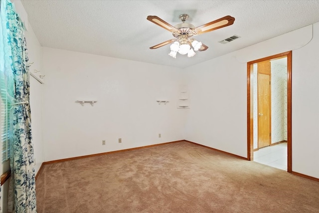 empty room with visible vents, light carpet, a ceiling fan, a textured ceiling, and baseboards