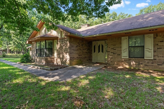 view of front facade featuring a front yard, brick siding, and a chimney