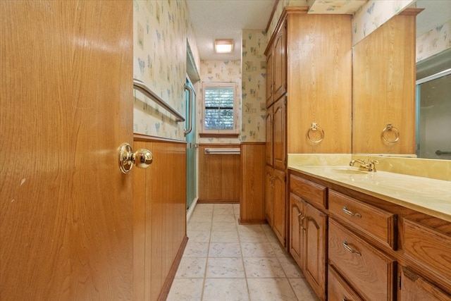 bathroom with wallpapered walls, vanity, a stall shower, and wainscoting