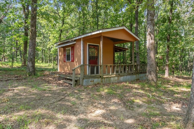 view of outdoor structure with a view of trees and a porch