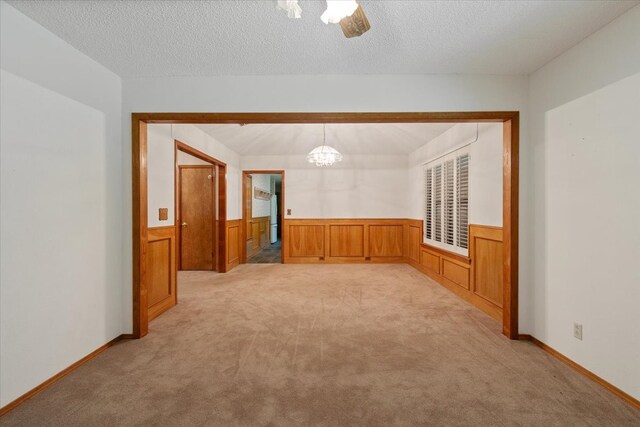 spare room with wainscoting, light colored carpet, and a textured ceiling