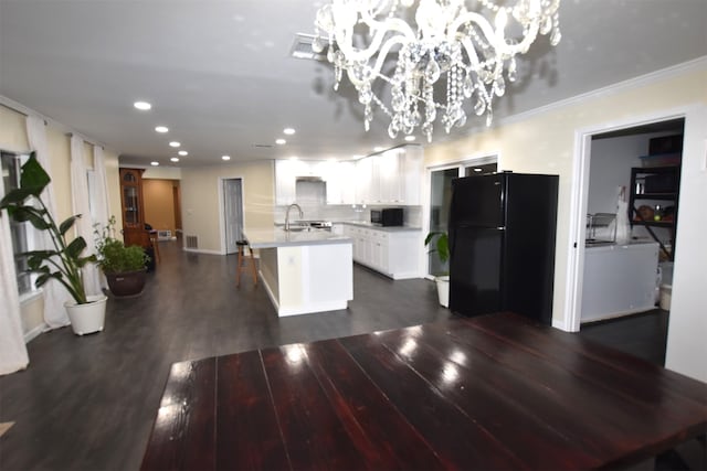 kitchen featuring a center island with sink, black appliances, dark wood-type flooring, a notable chandelier, and white cabinets