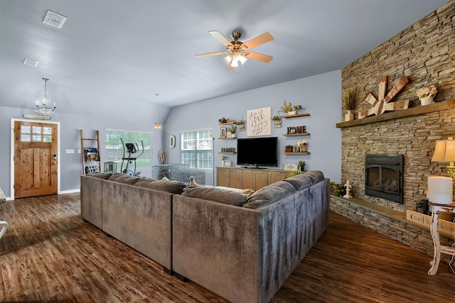 living room with vaulted ceiling, a stone fireplace, dark wood-type flooring, and ceiling fan