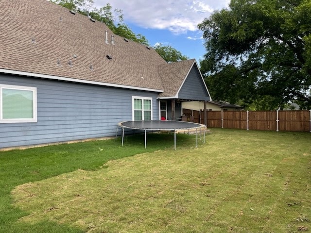 back of house with a yard and a trampoline