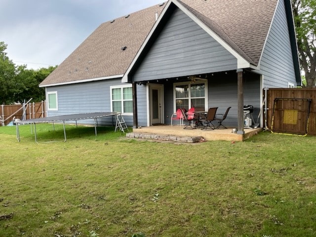 back of house with a lawn, a trampoline, and a patio