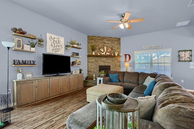 living room with ceiling fan, a stone fireplace, and light wood-type flooring